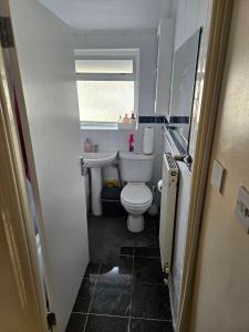 Elle comprend une petite salle de bains pourvue de toilettes et d'une fenêtre. dans l'établissement Comfortable single room in Family home, Heathrow airport, à Northolt