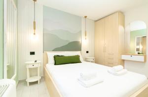 a white bedroom with a large bed and a mirror at 7 Hills Suites in Podgorica