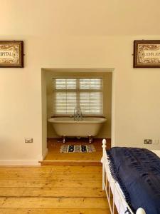 a bedroom with a bath tub and a window at Smugglers Lodge at Ventnor Botanic Garden in Ventnor