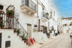 uma rua com edifícios brancos com escadas e vasos de plantas em La casa dei nonni em Cisternino