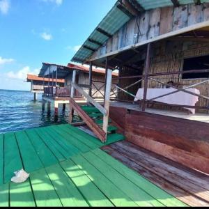 una casa en el agua con una cubierta verde en Cabañas sobre el mar en San Blas Narasgandub., en Nusatupo