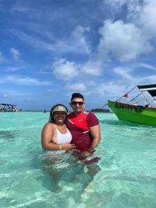 a man and woman sitting in the water in the ocean at Cabañas sobre el mar en San Blas Narasgandub. in Nusatupo