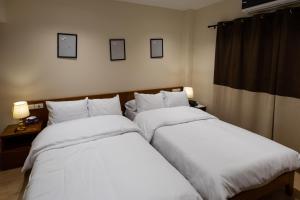 duas camas num quarto de hotel com lençóis brancos em Marron Serviced Studios and Rooms em Cairo