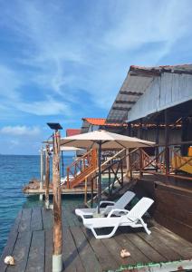 a dock with two lounge chairs and an umbrella at Cabañas sobre el mar en San Blas Narasgandub. in Nusatupo