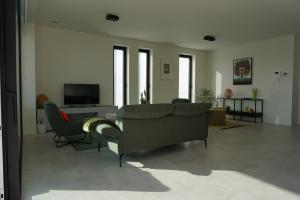 sala de estar con sofá, sillas y TV en Faro Greenpark APP 01, Cadzand-Bad, en Cadzand