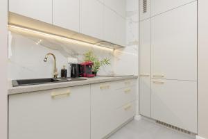 a kitchen with white cabinets and a sink at White & Gold Marble Apartment Łódź Fabryczna by Renters in Łódź