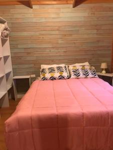 a bedroom with a pink bed with two pillows at Cabaña Pucón in Pucón