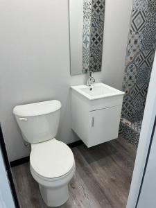 a bathroom with a white toilet and a sink at Huellas in Arecibo