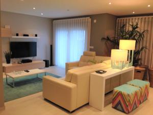 a living room with a couch and a tv at Holiday Calm Villa - Beach & Pool in Atouguia da Baleia