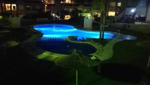 a swimming pool at night with blue illumination at Private Garden in Novamar 5 in Puerto Marino