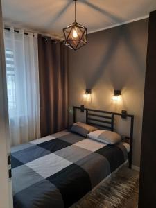 a bedroom with a bed with a black and white blanket at Apartamenty u Nataszy in Ustrzyki Dolne