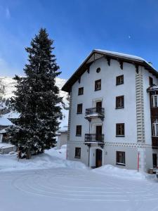 a large white building with a tree in the snow at Roccabella in Bivio