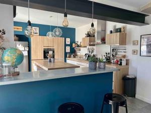 cocina con paredes azules y encimera con taburetes en MAGNIFIQUE VILLA D’ARCHITECTE avec piscine, en Saint-Laurent-dʼAigouze