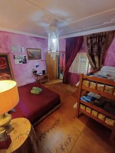 1 dormitorio con paredes de color púrpura, 1 cama y 1 mesa en Holt Hill, en Plettenberg Bay