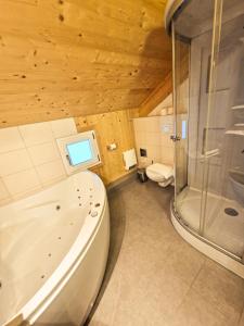 a bathroom with a tub and a glass shower at Kreischberg 14b - Chalet direkt am Skilift in Sankt Lorenzen ob Murau