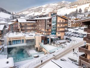 une station de ski avec une piscine dans la neige dans l'établissement Alpinresort ValSaa - Sport & Spa, à Saalbach-Hinterglemm