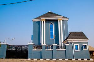 a blue building with a fence in front of it at Dopad Hills Hotel and Suites in Ojo