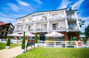 duży biały budynek z parasolami przed nim w obiekcie Porto Marina w mieście Krynica Morska
