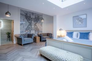1 Schlafzimmer mit einem großen Bett und 2 Stühlen in der Unterkunft Suite 15 - Sleeping Giant Hotel - Pen Y Cae Inn in Brecon