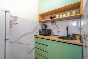 una cocina con armarios verdes y fregadero en 7 Hills Suites, en Podgorica
