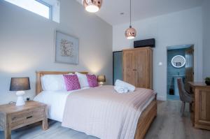 a bedroom with a bed with pink pillows and a table at Suite 12 - Sleeping Giant Hotel - Pen Y Cae Inn in Brecon