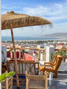 un patio con sillas y una sombrilla de paja en Paddle Out Morocco en Tamraght Ouzdar