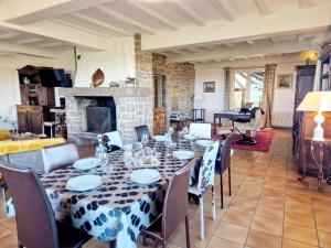 a dining room with a table and chairs and a fireplace at Les Tamaris **** YourHostHelper in Omonville-la-Rogue