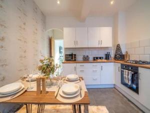 a kitchen with white cabinets and a wooden table at Pass the Keys Elegant Home with free Parking in Nottingham