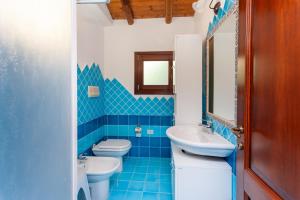 een blauw betegelde badkamer met 2 toiletten en een wastafel bij Casa Teodoro in San Teodoro +56 foto's