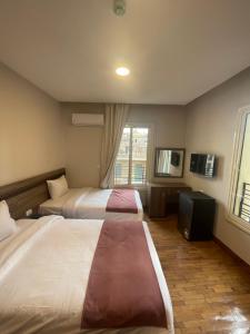 Cette chambre comprend deux lits et une télévision. dans l'établissement New Lotus Hotel, au Caire