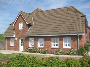 a red brick house with a brown roof at Direkt am Deich - Ferienwohnung Föhr im Gästehaus Am Badedeich in Dagebüll