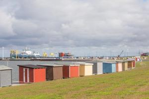 a row ofsheds in a field next to a body of water at Direkt am Deich - Ferienwohnung Oland im Gästehaus Am Badedeich in Dagebüll +3 photos