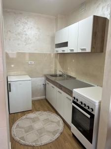 a kitchen with white cabinets and a sink and a stove at Apartman Ano LUX in Novi Pazar