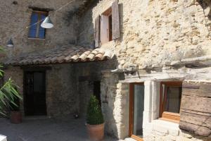 a stone building with a potted plant in front of it at La ferme de blanche in Entrechaux