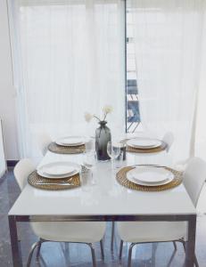 a white dining room table with white plates and chairs at Gtrip P Faliro Coastal Comfort 5F in Athens