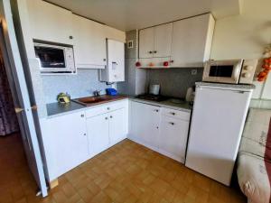 a kitchen with white cabinets and a white refrigerator at 001 Sentosa A15 in Cap d'Agde