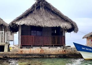 una pequeña cabaña con un barco en el agua en Isla narasgandub cabaña en tierra, en Nusatupo