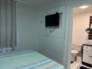 a bedroom with a bed and a tv on the wall at Suítes e quartos no Centro de Blumenau in Blumenau