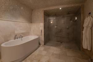 een badkamer met een bad en een douche bij Artemis Cave Suites & Spa- Adults Only in Goreme