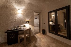 baño con tocador con espejo y silla en Artemis Cave Suites & Spa- Adults Only, en Göreme