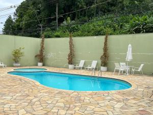 a swimming pool with chairs and umbrellas in a courtyard at Suítes e quartos no Centro de Blumenau in Blumenau