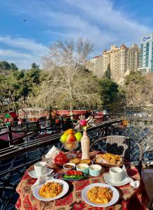 une table avec des assiettes de nourriture sur un balcon dans l'établissement Nizami Central Street Hotel, à Baku