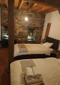 a bedroom with two beds and a stone wall at To Apokentro in Alona