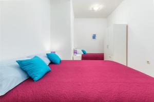 a bedroom with a large red bed with blue pillows at Sweet and Cozy apartments Luciano - Fažana in Fažana