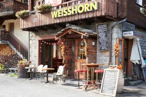 un restaurant avec des tables et des chaises à l'extérieur d'un bâtiment dans l'établissement Hotel Weisshorn, à Zermatt