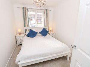1 dormitorio con cama blanca y almohadas azules en Serenity en Freshwater