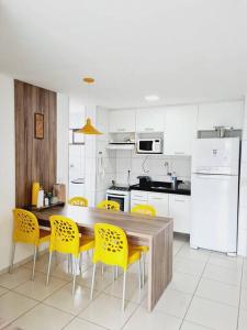 a kitchen with a wooden table and yellow chairs at Ap. Novo Maceió - praia de Ponta verde in Maceió