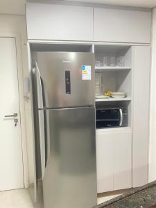 um frigorífico de aço inoxidável numa cozinha branca em Meireles Compact Apartamento 500m da praia em Fortaleza