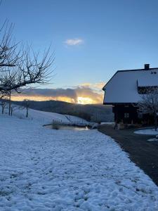 un camino cubierto de nieve junto a un edificio con la puesta de sol en el fondo en Kapellenhof Ferienwohnungen, en Triberg