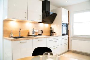a kitchen with white cabinets and a table at Gemütliches Design Appartment in Wolfsburg in Wolfsburg